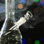 Closeup,View,Of,Glass,Bong,With,Smoke,Against,Blurred,Lights.