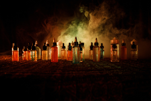 Vape,Concept.,Smoke,Clouds,And,Vape,Liquid,Bottles,On,Dark