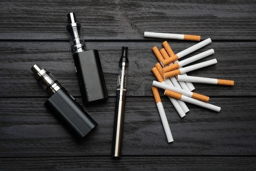 Cigarettes,And,Different,Vaping,Devices,On,Black,Wooden,Background,,Flat